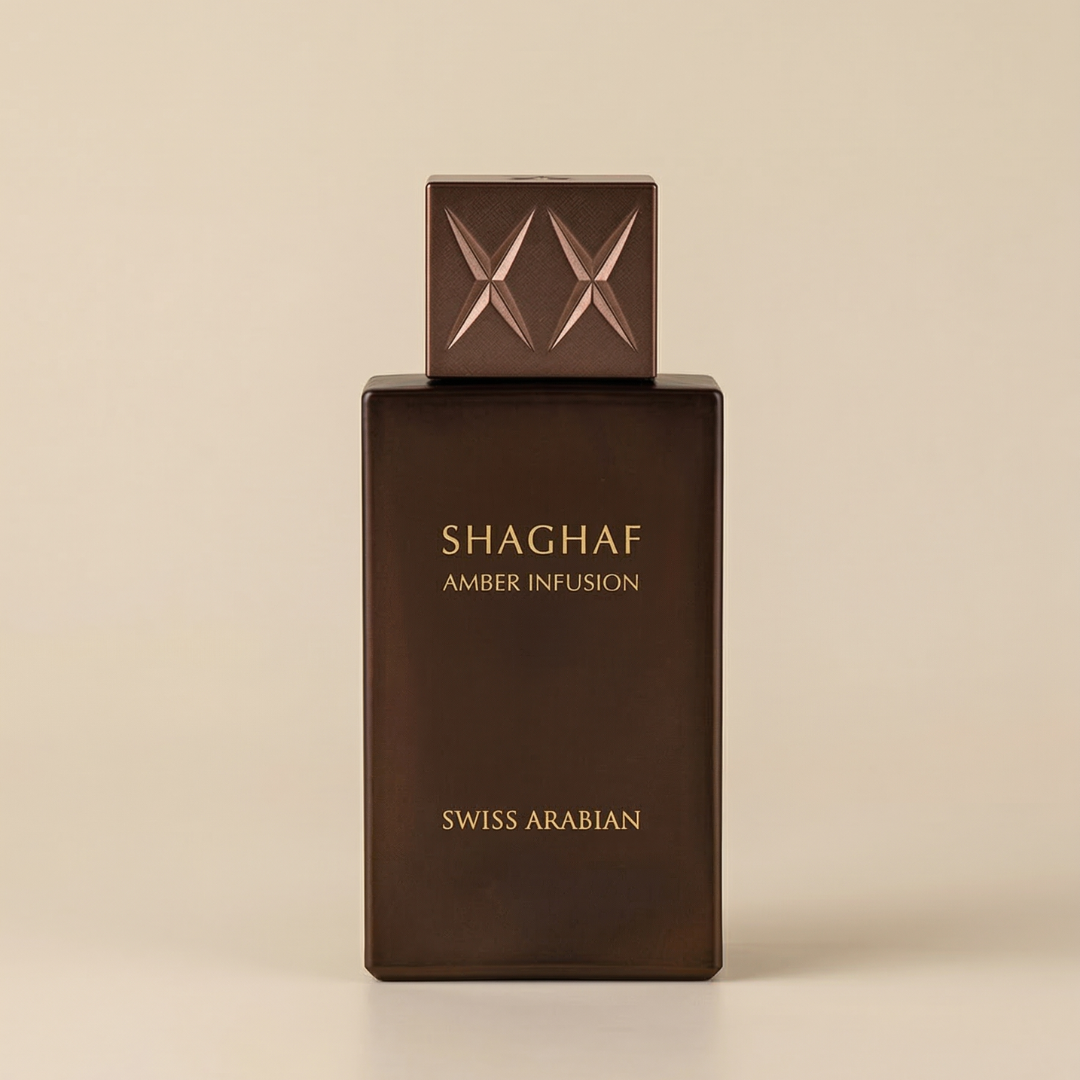 A rectangular brown bottle labeled "Shaghaf Amber Infusion 75ml EDP - Swiss Arabian" with a patterned cap stands against a neutral background, reflecting the long-lasting amber fragrance by Swiss Arabian.