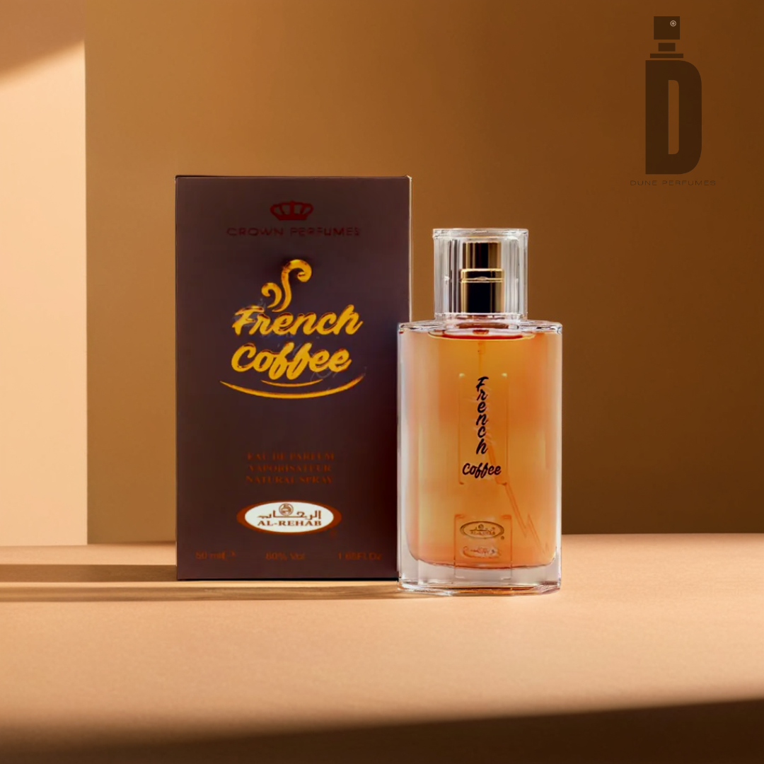 A 50ml bottle of Al Rehab's French Coffee EDP, enriched with notes of vanilla, sits before its branded box on a brown surface. The amber-hued liquid stands out stylishly against the packaging, which features a logo and text in both English and Arabic. Soft lighting enhances the warm ambiance.