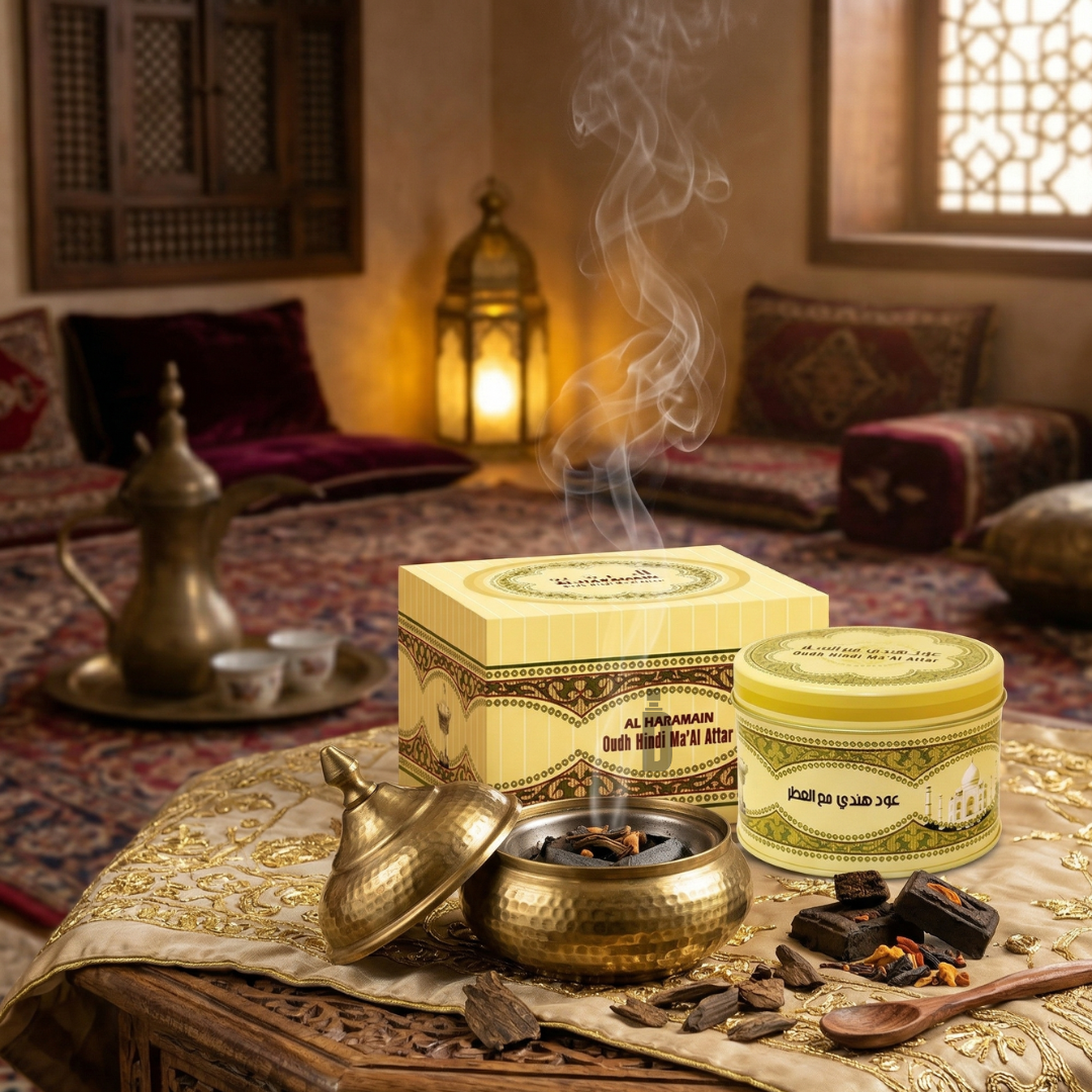 An ornate room with cushions and Arabian decor features Al Haramain’s Oudh Hindi Ma'al Attar Bakhoor 50G, traditional incense burners, bakhoor, and oud wood. Oriental fragrances fill the air as smoke gently rises from the incense.