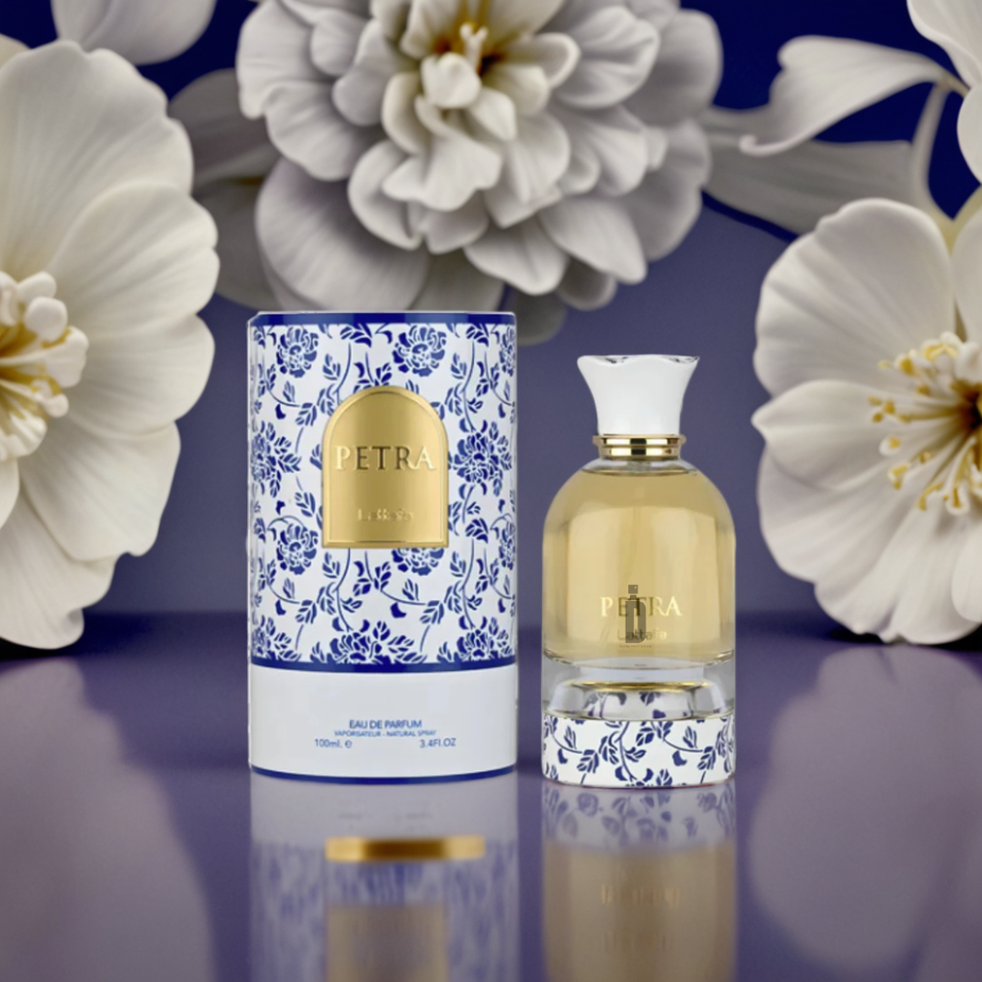 A bottle of Lattafa Petra 100ml EDP is displayed beside its blue and white floral box on a glossy surface, with large white flowers in the background, creating an elegant scene that highlights this bold Lattafa fragrance.