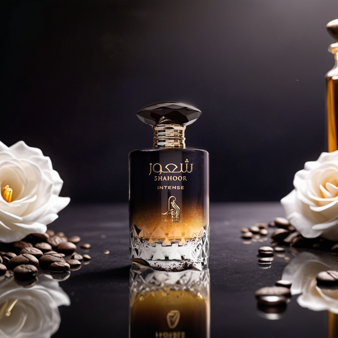The Shahoor Intense 100ml EDP by Al Absar stands on a reflective surface amid white roses and coffee beans, evoking the amaretto notes of this luxurious Eau de Parfum against a dark, elegant backdrop.