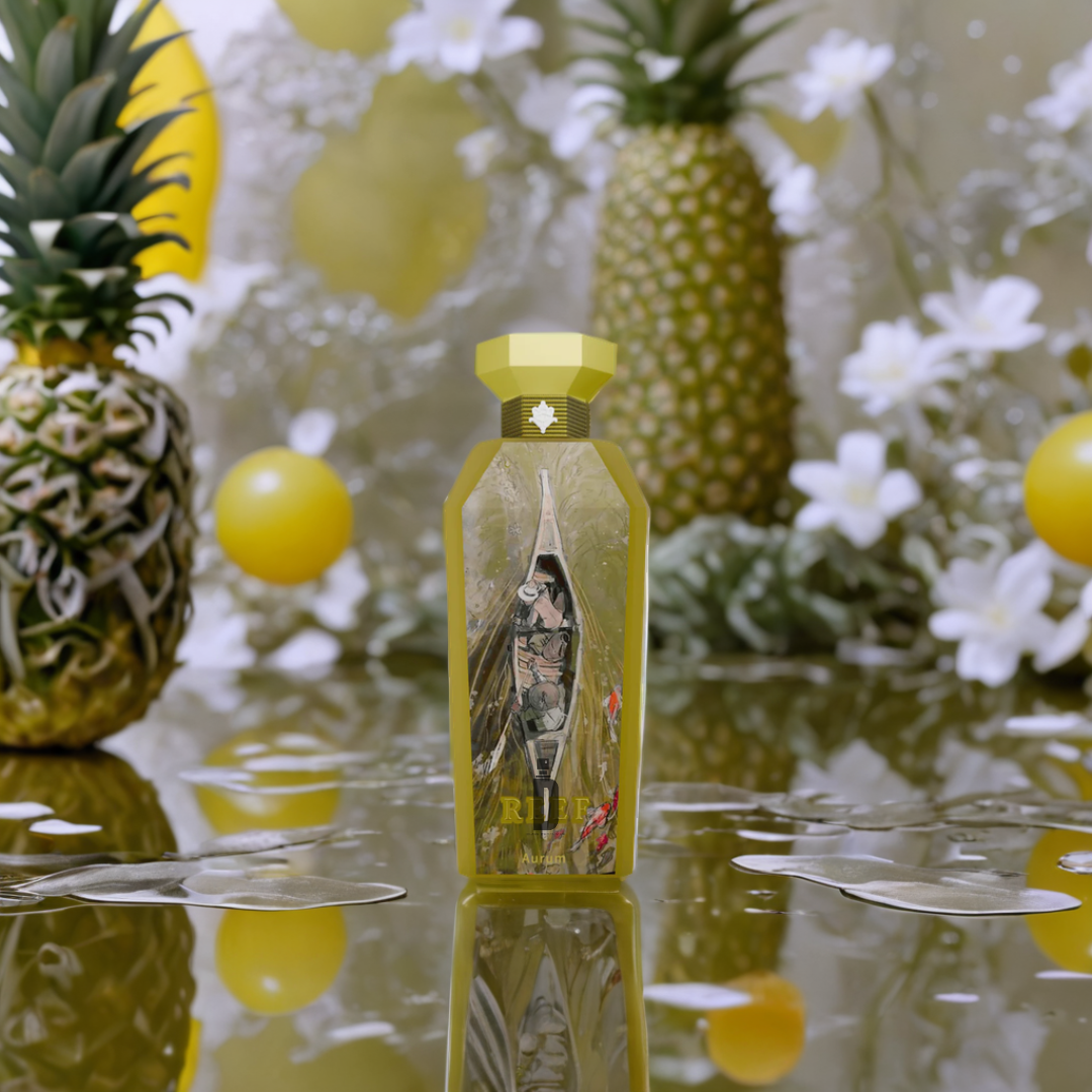 A vibrant yellow bottle of Aurom 150ml EDP by Reef sits on a reflective surface, encircled by pineapples, white flowers, and yellow balloons, evoking a tropical aroma with scattered water droplets enhancing the scene.