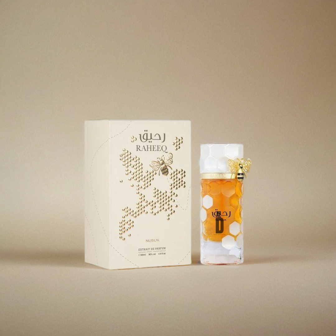The Raheeq 100ml EDP by Nusuk features a honeycomb bottle with a gold bee on the lid, displayed beside its cream-colored box labeled "RAHEEQ," offering a sweet magnolia coconut scent inspired by golden bee accents.