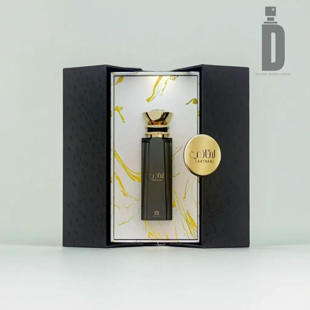 An elegant perfume bottle stands in an open black box with gold accents and marbled gold lining. The black bottle, featuring gold lettering and a gold cap, holds Laathani 80ml EDP - Ahmed Al Maghribi with rich Bakhoor Accords. The logo for Ahmed Al Maghribi is in the top right corner.