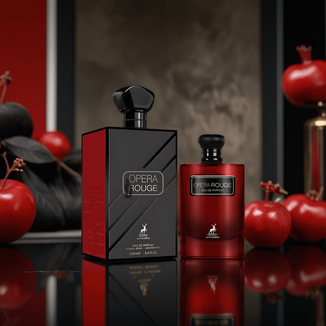 Two bottles of Opera Rouge 100ml EDP by Maison Alhambra, one in black and one in red, sit on a glossy surface amid red apples and black decor, creating an elegant and luxurious atmosphere.