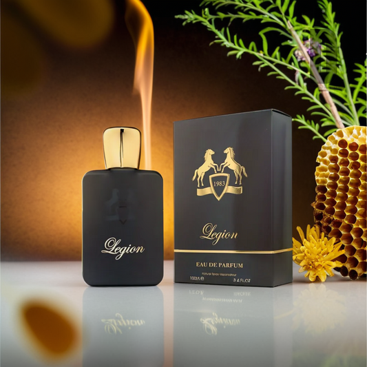 A black and gold bottle of Legion 100ml Eau de Parfum by Fragrance World stands next to an ornate black and gold box featuring two rearing horses. The background includes cinnamon honey osmanthus, green leaves, and vibrant yellow flowers, creating a warm, glowing ambiance.