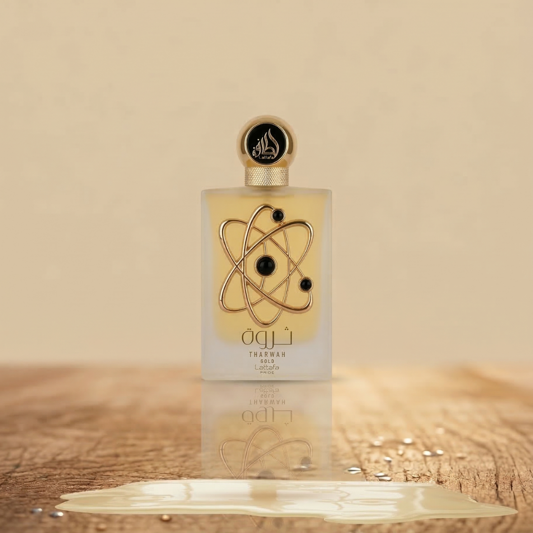 Tharwah Gold 100ml EDP by Lattafa stands on a wooden surface with spilled liquid. Its gold, atom-inspired bottle and black-and-gold cap reflect elegance, promising a luxurious scent from the renowned Lattafa brand.