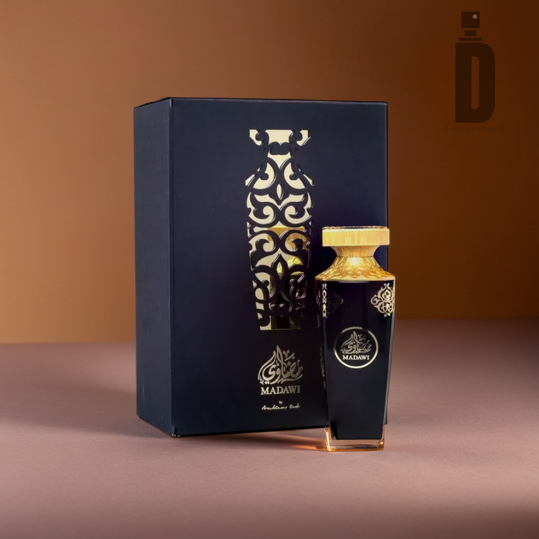 A bottle of Madawi - Arabian Oud, crafted by Arabian Oud, exudes sophistication with its intricate design and golden cap as it stands gracefully before its ornate black box. The box displays a stylized pattern along with the product name in silver set against a warm brown backdrop.