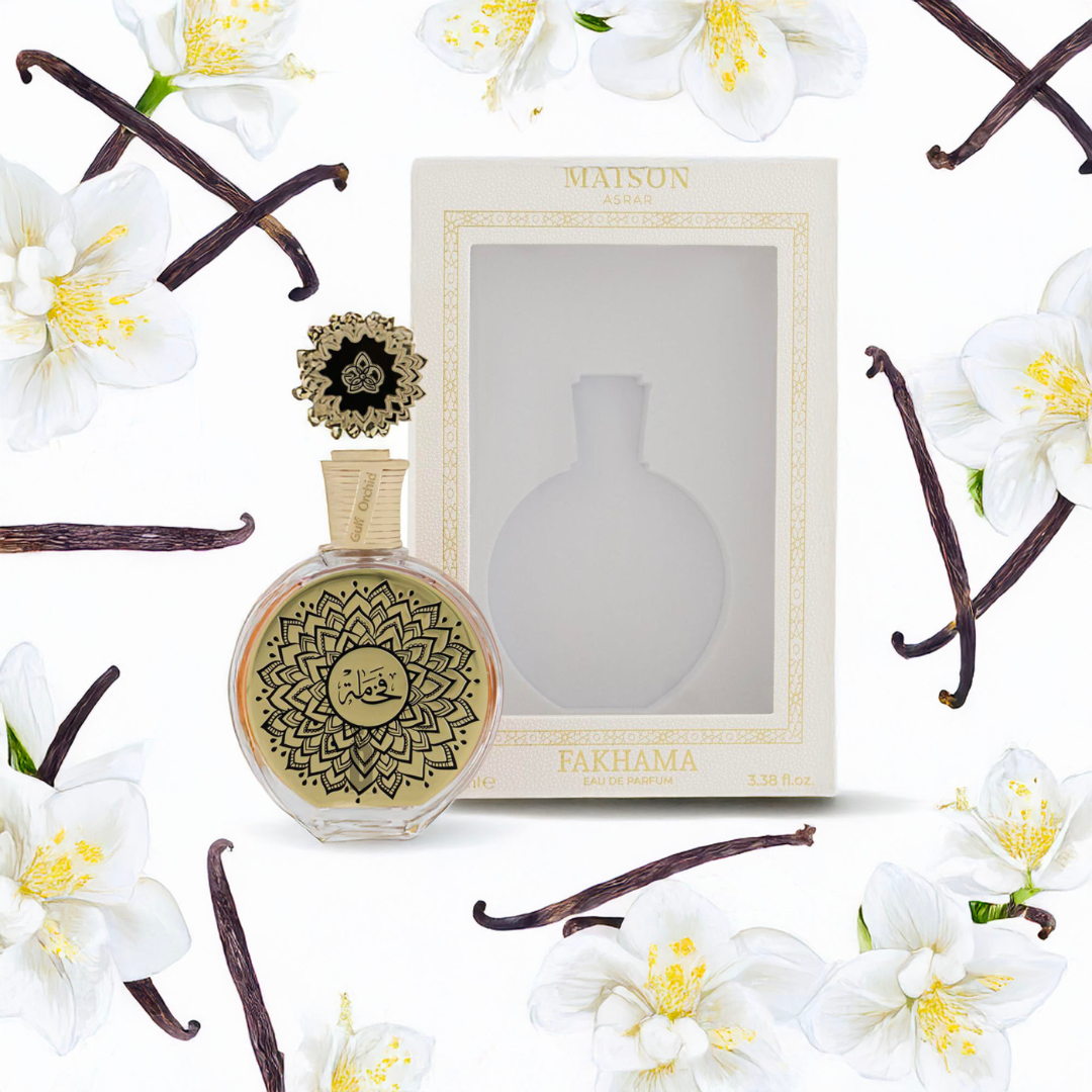 The Fakhama 100ml by Maison Asrar from Gulf Orchid boasts ornate gold and black details, capturing the essence of a luxury fragrance. It rests among white flowers and vanilla beans with elegance, against a pristine white background next to its floral-patterned box.