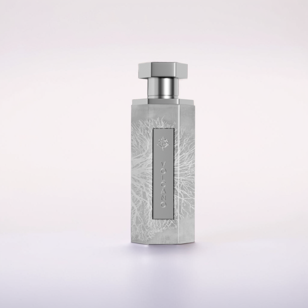 The Volcano 200ml EDP by Reef features a textured, frosty geometric bottle with a hexagonal cap and vertical label. Its fiery fragrance emanates from subtle, intricate patterns like volcanic ash, set against a light and soft backdrop.