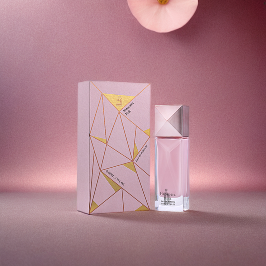 The Habanera Pink 100ml EDP by Aurora Scents features a pink box with gold geometric lines next to its matching bottle, accented by a soft orchid and shimmering background—a graceful scene for this floral-fruity fragrance.