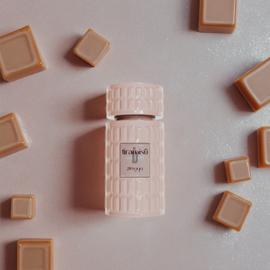 A pink, textured Tiramisu Caramel 100ml EDP by Afnan (Zimaya) rests on a sparkly surface amid caramel squares, evoking the irresistible caramel notes of this gourmand fragrance.