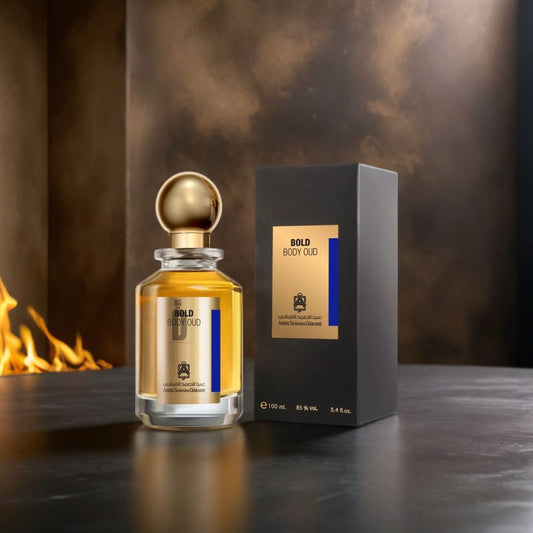 A glass Bold Body Oud 100ml EDP by Abdul Samad Al Qurashi, with a gold cap, stands beside its black and gold box on a dark surface as flames glow in the background, evoking the warm allure of this oriental Eau de Parfum.