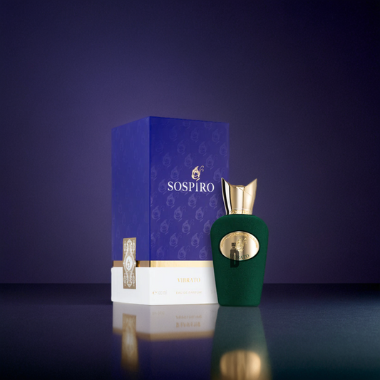 The Sospiro Vibrato 100ml EDP perfume with a gold cap stands next to its purple and gold box against a dark gradient background, highlighting the elegance of this Sospiro fragrance.