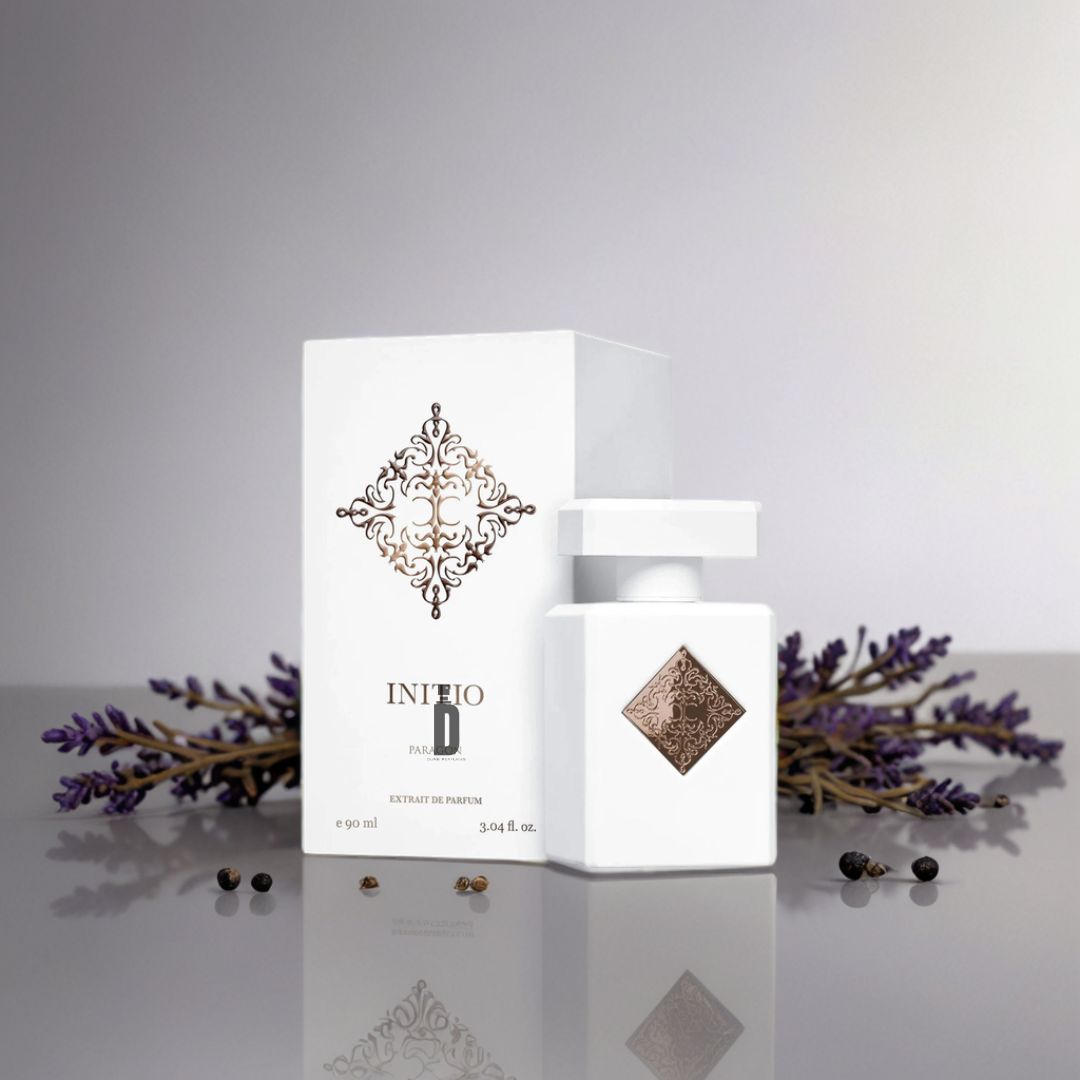 A white Paragon 90ml EDP bottle and box by Initio Parfums Prives are displayed on a reflective surface, accented by lavender and peppercorns, suggesting a spiritual, wisdom-inspired fragrance.