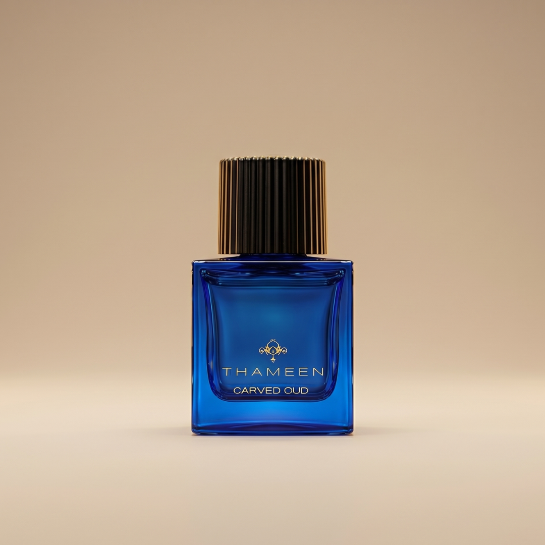 A blue glass bottle of Thameen's Carved Oud 100ml EDP, with a black and gold ribbed cap, is displayed against a beige background—a refined showcase for this luxurious fragrance.