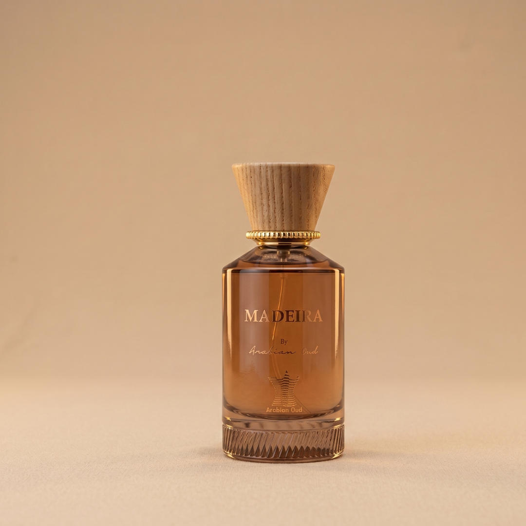 A glass bottle of Madeira 100ml EDP by Arabian Oud, featuring a wooden cap, rests on a beige surface that complements its woody-oriental fragrance and elegant design.