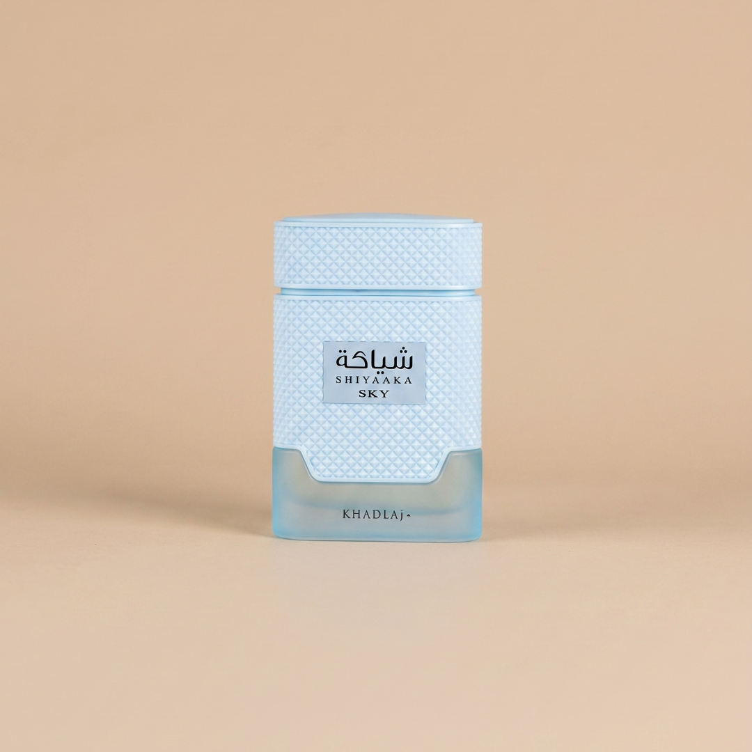 A light blue bottle of Shiyaaka Sky 100ml EDP by Khadlaj stands upright on a beige background. The bottle features a textured pattern and a square label displaying text in both Arabic and English, reflecting the signature style of this Khadlaj fragrance.
