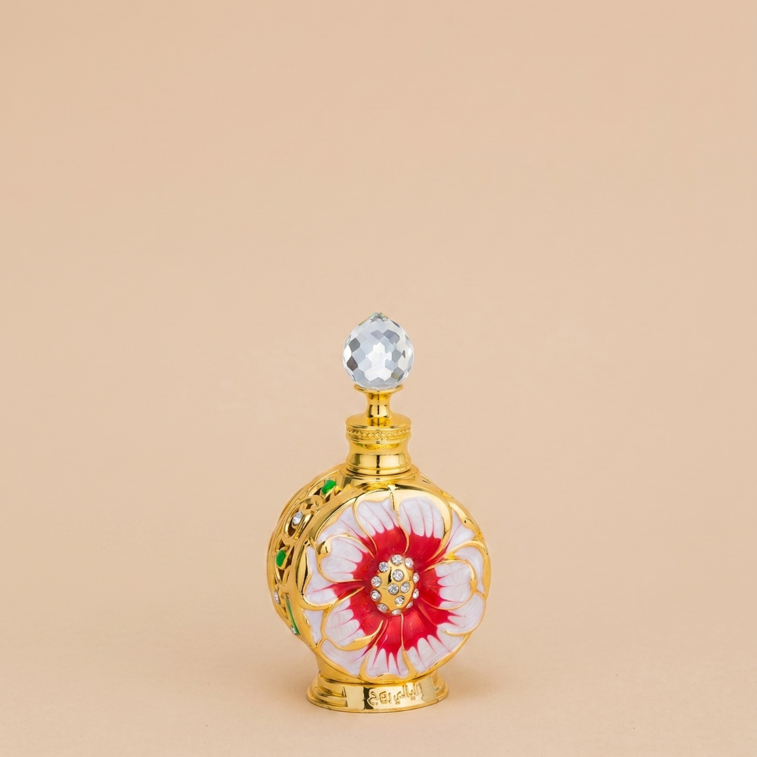 A decorative Swiss Arabian Layali Rouge 15ml Perfume Oil bottle, featuring gold accents, a bold red and white floral design, and a faceted crystal-like stopper, hints at the tropical fragrance within. The product is displayed against a plain beige background.