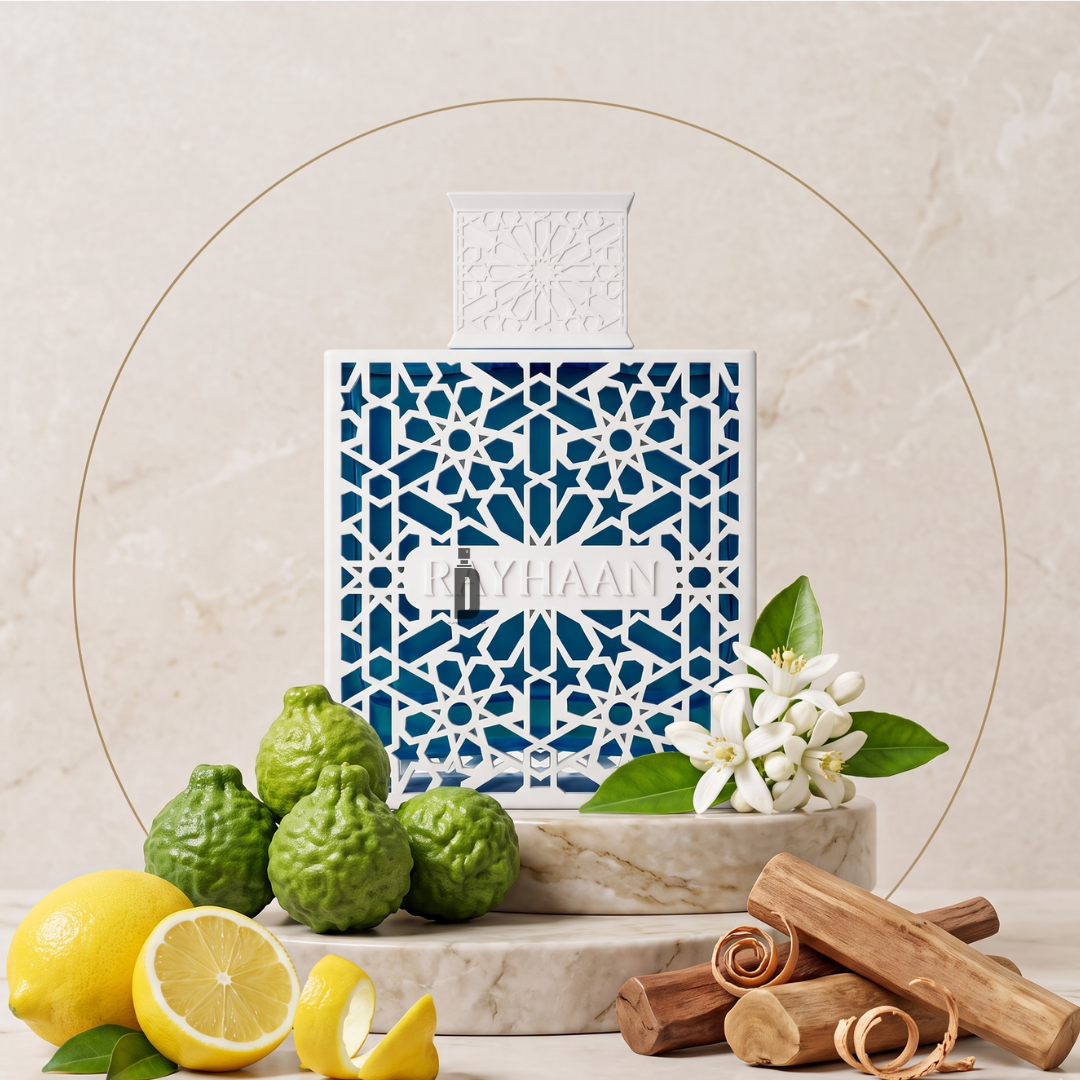 Azul 100ml EDP by Rayhaan, in a blue and white geometric bottle on marble, is surrounded by lemons, bergamot, white flowers, green leaves, and cinnamon sticks—capturing its fresh and aquatic fragrance notes.