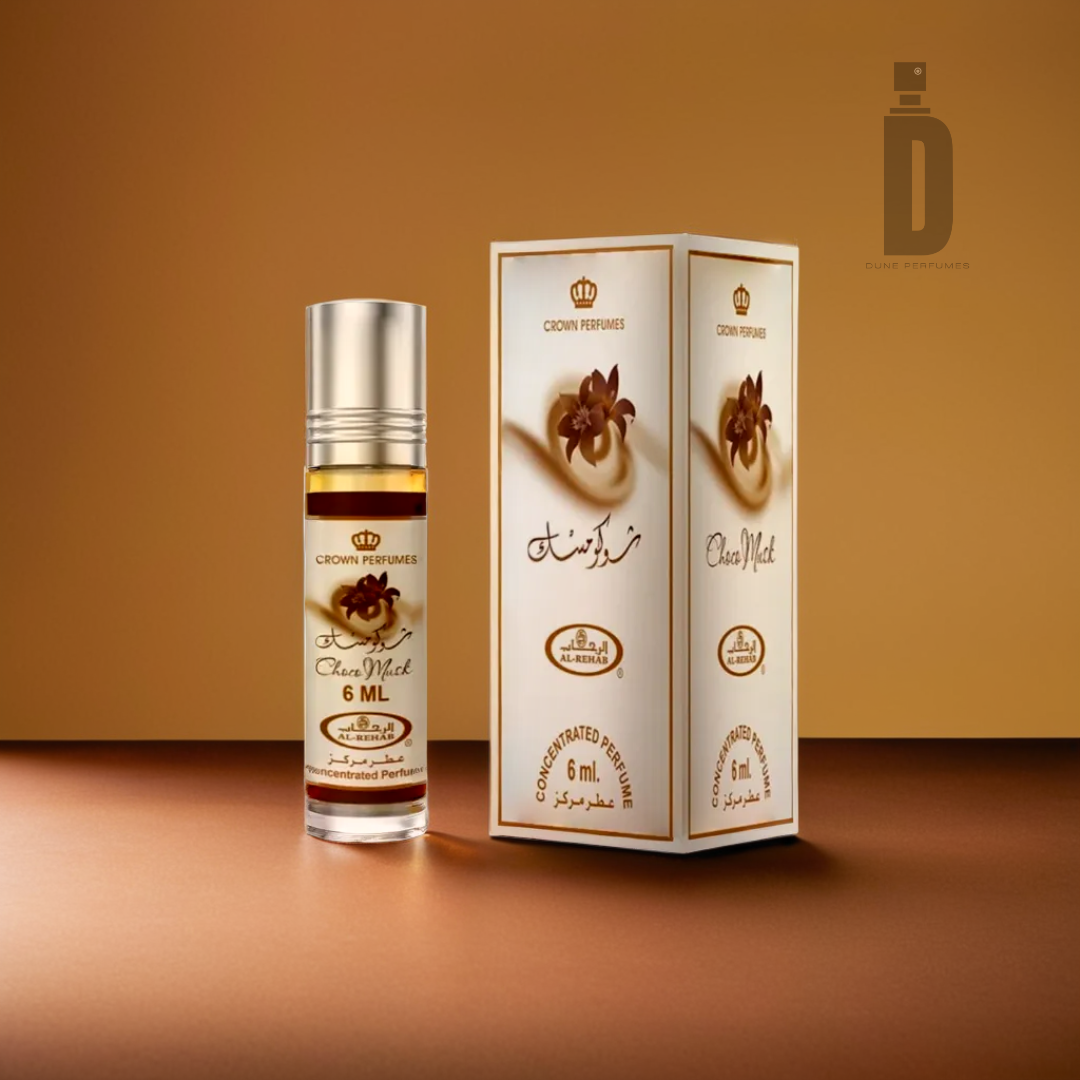 A bottle of Al Rehab Choco Musk concentrated perfume oil is pictured next to its white and gold packaging on a gradient brown surface. The 6 ml bottle, featuring a silver cap, exudes a musky fragrance. The Al Rehab logo is elegantly displayed in the background.