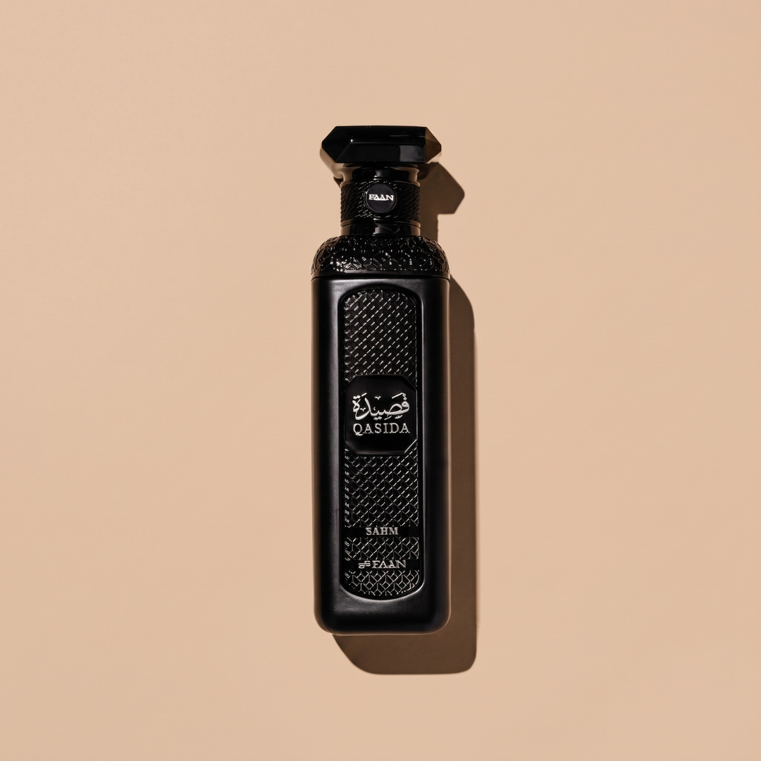 A black perfume bottle labeled “Qasida Sahm 200ml EDP - Faan Perfumes” by Faan Perfumes stands upright on a beige background, casting a shadow to the right. The bottle displays textured patterns and a dark, faceted cap—an elegant presentation that reflects the sophistication of this oud fragrance.
