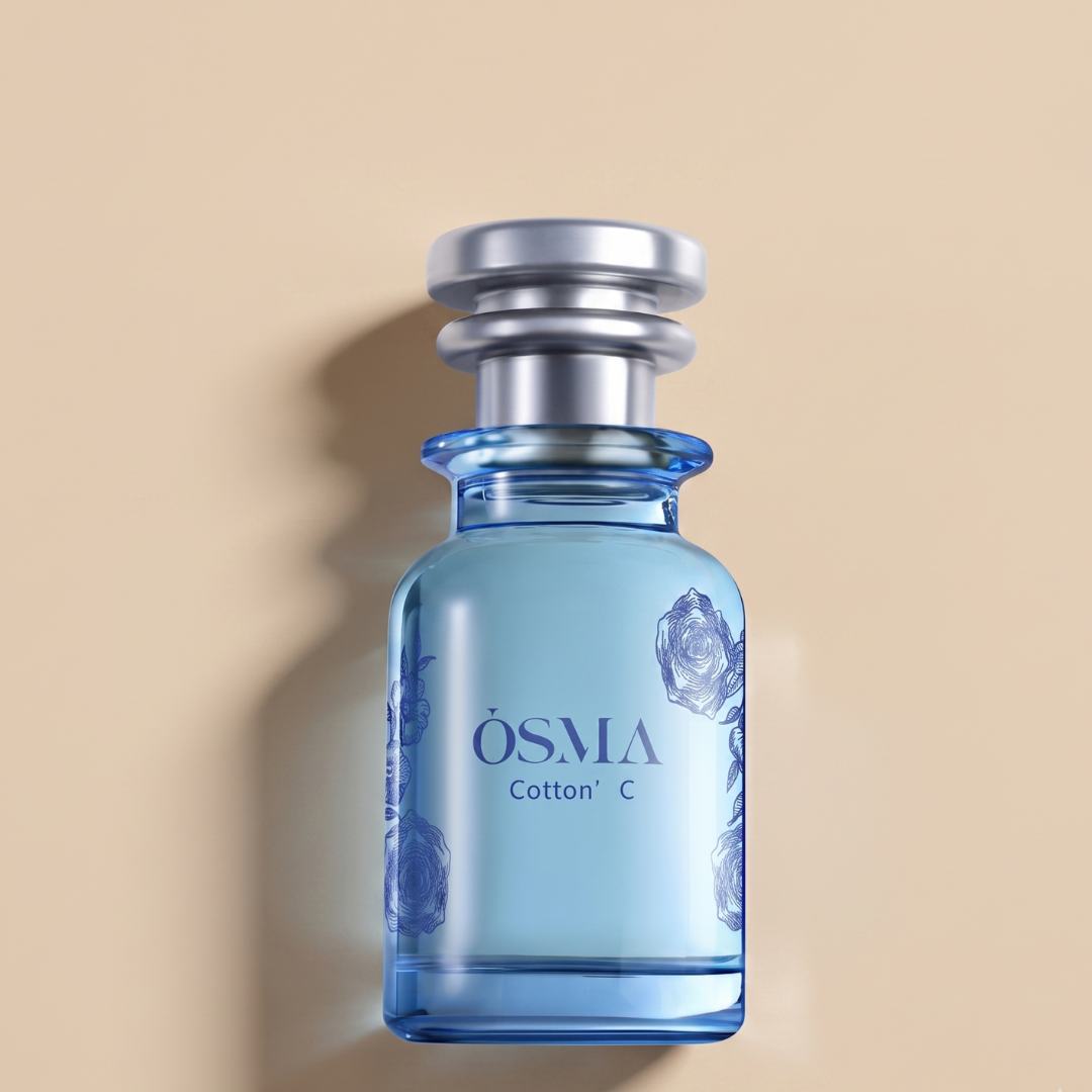 A blue glass bottle labeled "Cotton C 75ml EDP - Osma" with floral designs and a silver cap sits on a beige background with a soft shadow—an elegant woody perfume from Osma, evoking sandalwood oud.