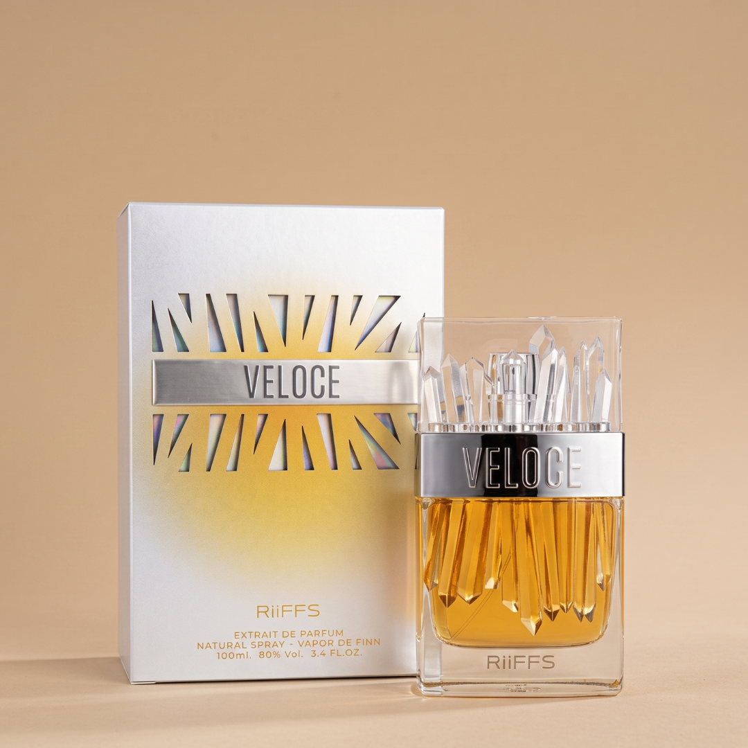 A 100ml bottle of veloce EDP by Riiffs, featuring a silver cap and geometric gold-accented designs on both the bottle and matching box, displayed against a beige background.