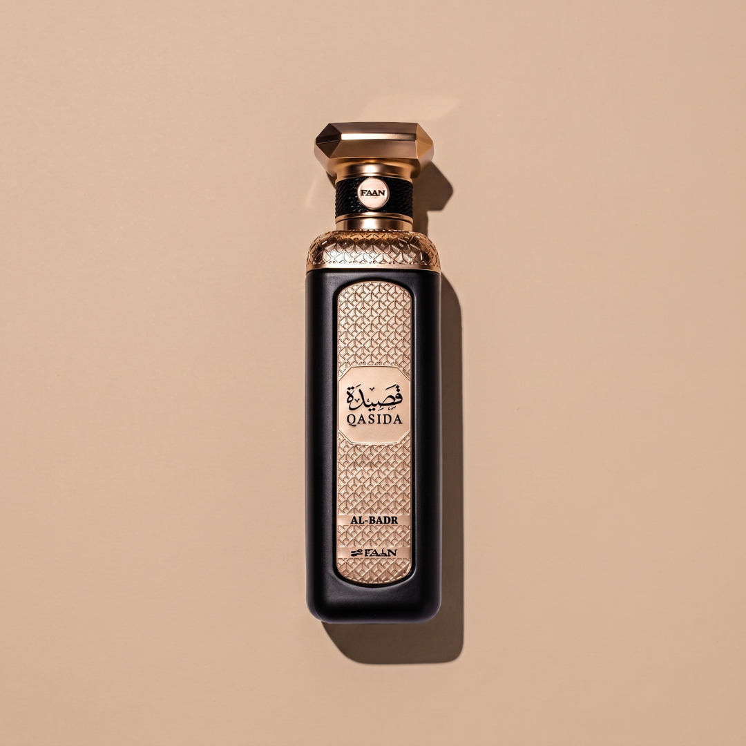 A gold and black bottle of Qasida Al-Badr 200ml EDP from Faan Perfumes, featuring intricate decorative patterns, stands centered against a light beige background—beautifully reflecting the allure of this captivating fragrance.