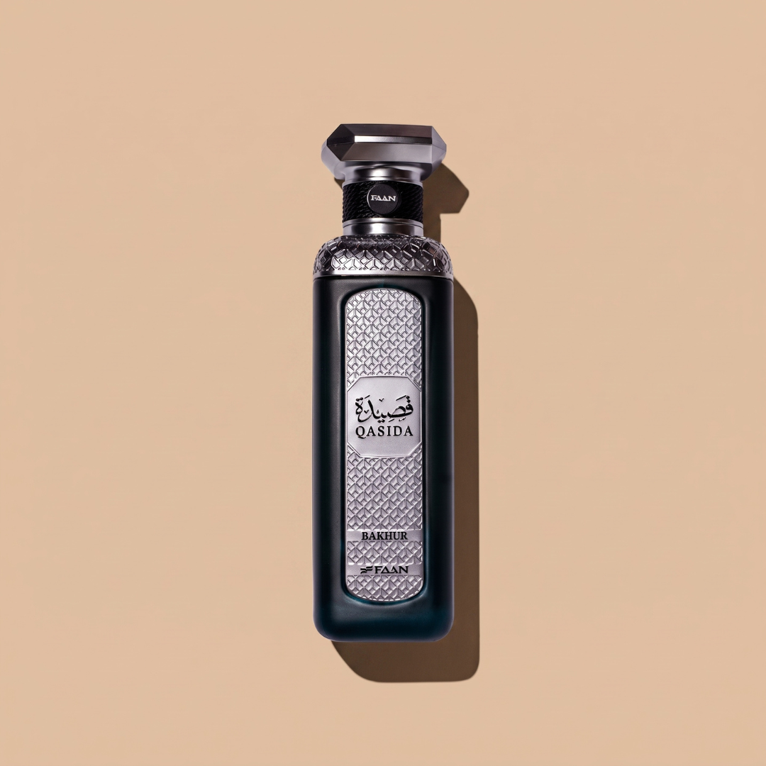 A silver and black perfume bottle labeled “Qasida Bakhur” by Faan Perfumes stands upright on a beige background, casting a shadow to the right. The bottle showcases a textured pattern and Arabic script on its front, reflecting the luxurious essence of Qasida Bakhur 200ml EDP—a sophisticated fragrance blend from Faan Perfumes infused with rich sandalwood notes.