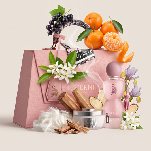 A bottle of Laverne Sense Collection 75ml EDP is styled alongside pink flowers, tangerines, blackcurrants, wood, ginger, cotton, and spices. This luxurious still-life arrangement evokes a fresh and distinctly feminine fragrance from the Laverne brand.