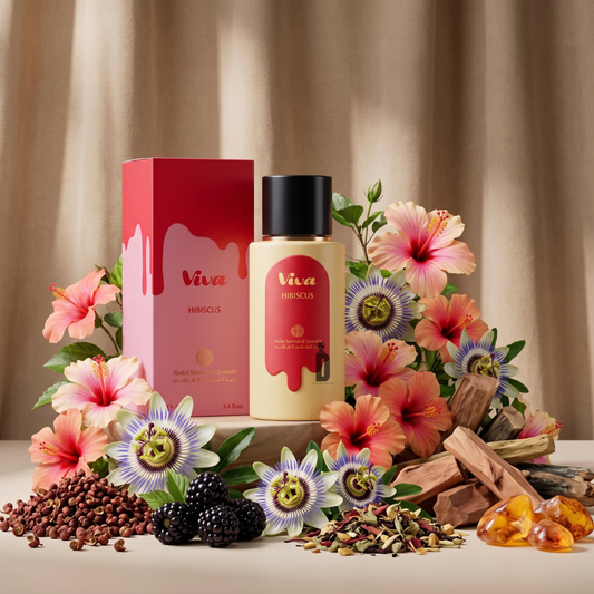 A bottle and box of Viva Hibiscus 100ml EDP by Abdul Samad Al Qurashi are elegantly displayed amidst hibiscus flowers, passion flowers, blackberries, seeds, sandalwood, and golden resin, set against a soft beige curtain backdrop—evoking the vibrant essence of this exquisite floral fragrance.