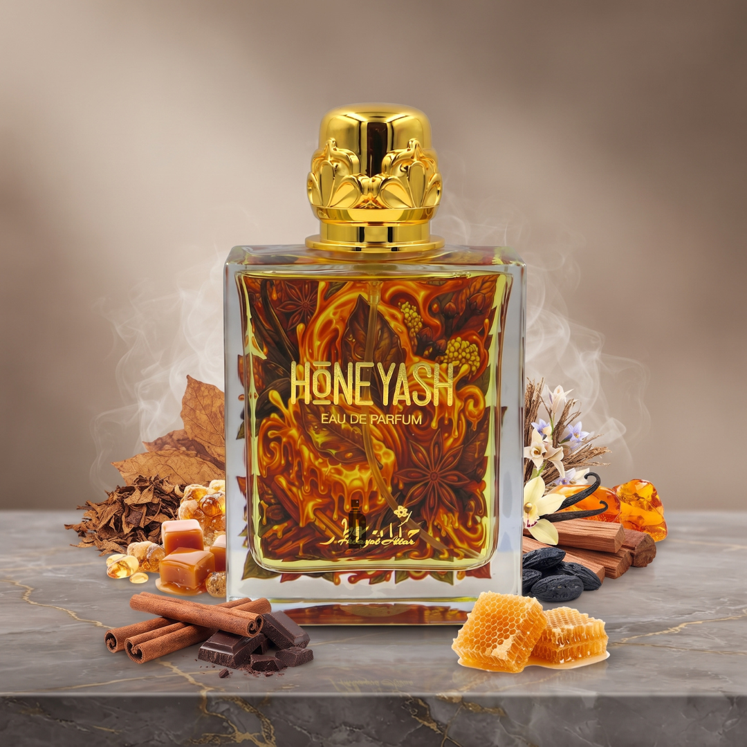 A bottle of Hekayat Attar’s HoneyAsh 100ml EDP rests on marble, encircled by cinnamon sticks, honeycomb, vanilla, leaves, and blossoms, as delicate wisps of aromatic mist evoke the enchanting oriental honey gourmand essence that inspired its creation.