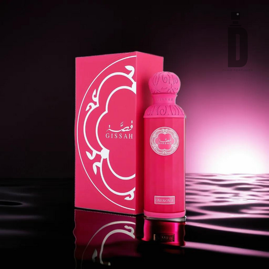 A vibrant pink One & Only 200ml EDP - Gissah perfume bottle with an intricate design stands next to a matching box on a reflective surface. The background features a gradient from dark to light pink, giving a luxurious feel. This sophisticated Floral Fruity fragrance by Gissah leaves a lasting impression. Elegant white detailing and branding adorn both the box and bottle.