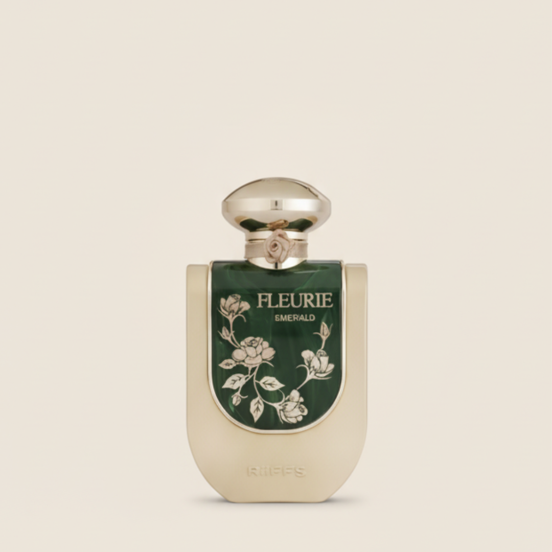 The Fleurie Emerald 100ml EDP by Riiffs comes in a gold bottle with a rounded cap and a dark green label featuring white floral designs and "FLEURIE EMERALD"; the Riiffs brand is embossed at the base.