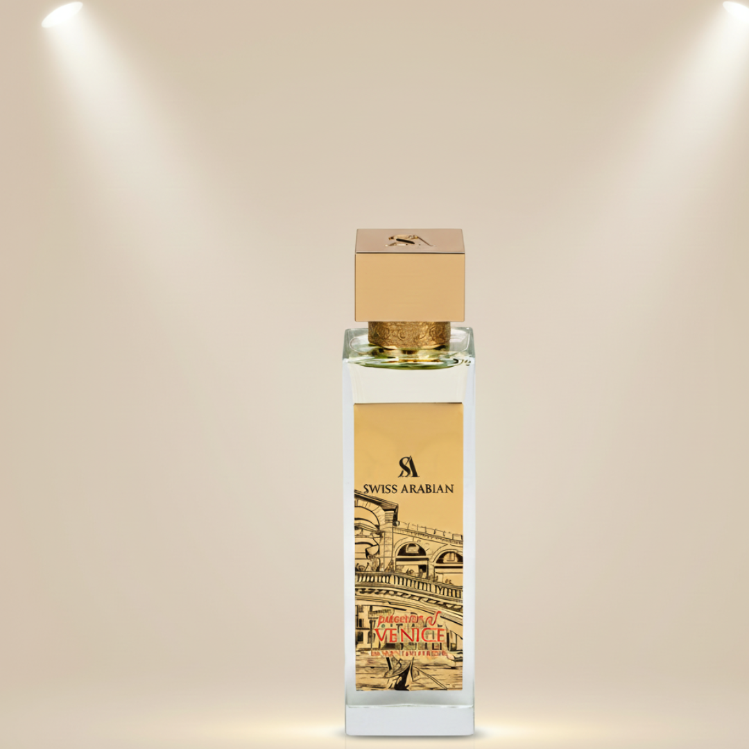 A clear glass bottle with a gold cap displays the Swiss Arabian logo and "Venetia" in red, set against an illustrated cityscape. Passion Of Venice 100ml EDP by Swiss Arabian evokes patchouli and jasmine notes against a beige background.