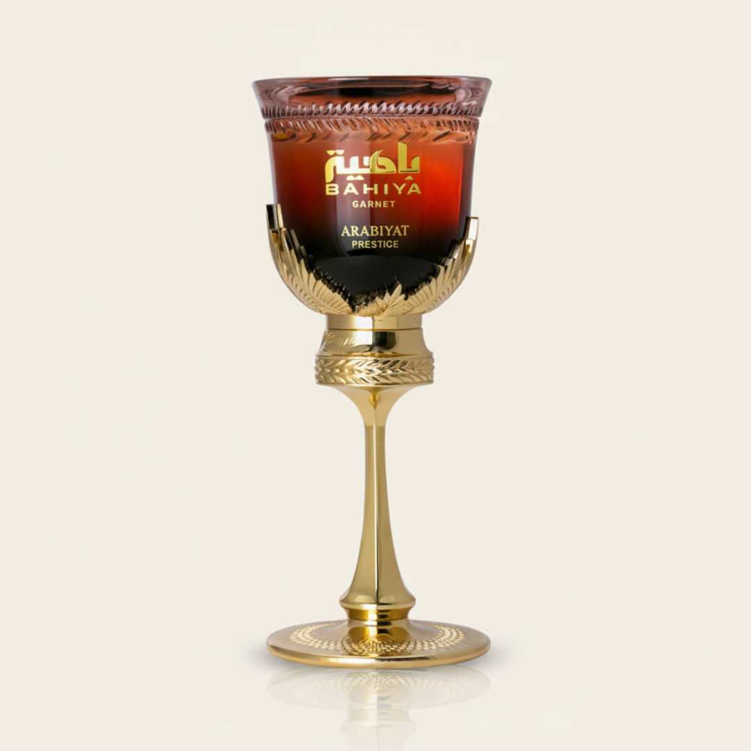 A decorative goblet with a gold stem and base holds a deep red cup labeled "Bahiya Garnet 100ml EDP - Arabiyat Prestige," evoking a fruity summer fragrance, set against a plain light background.