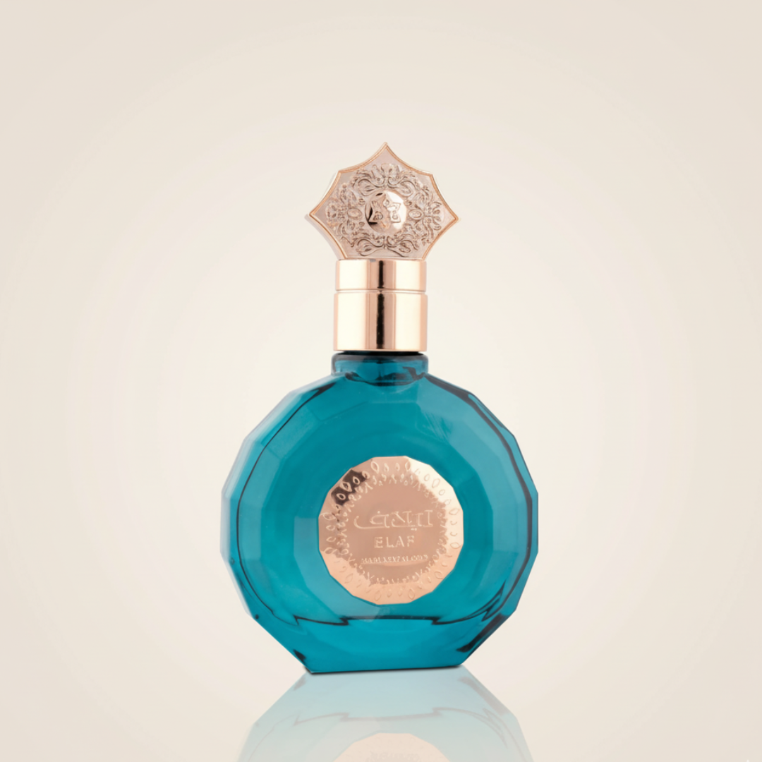 A faceted blue perfume bottle, Elaf 100ml EDP by Mamlakat Al Oud, with a gold ornate cap and label featuring decorative script and patterns, sits against a light beige background, evoking the essence of luxury fragrance.
