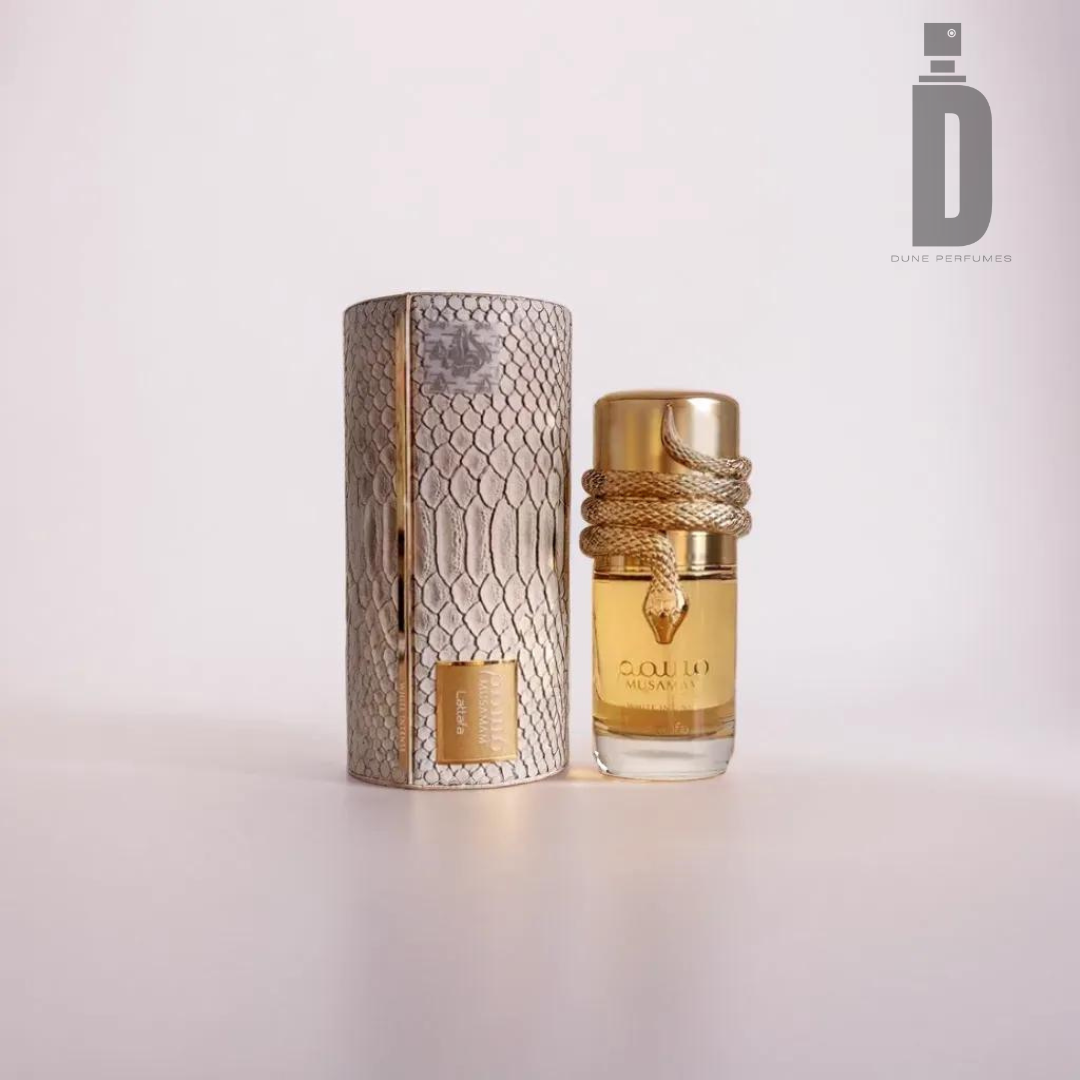 A luxury perfume bottle from Lattafa, labeled as "Musamam White Intense 100ml EDP," features a gold cap and decorative braided rope. This sophisticated fragrance is presented alongside its cylinder-shaped packaging adorned with a snakeskin pattern. The Dune Perfumes logo is visible in the upper right corner.