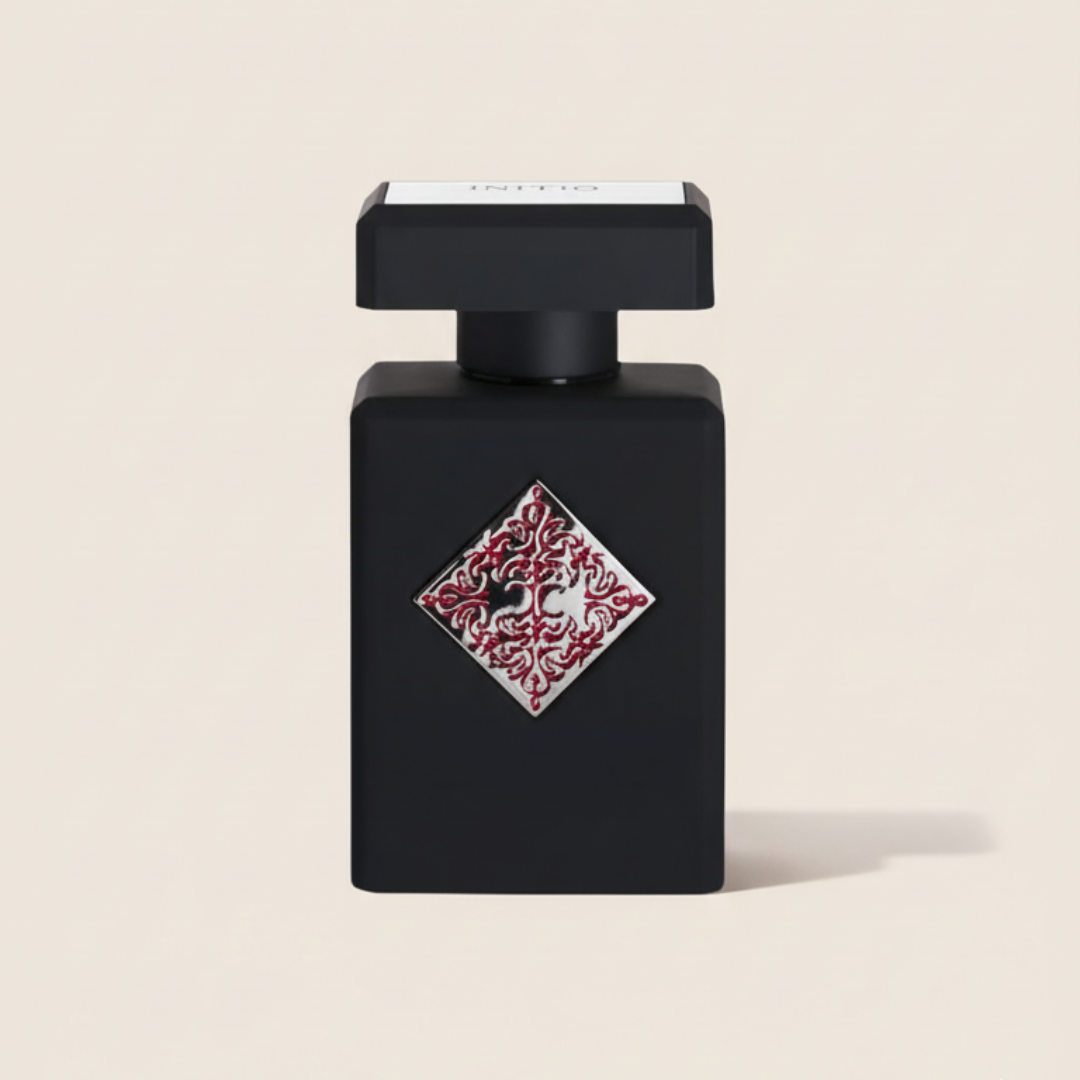 The Absolute Aphrodisiac 90ml EDP by Initio Parfums Prives features a black rectangular bottle with a square cap and a striking red and silver diamond emblem, evoking a seductive amber fragrance against a light background.