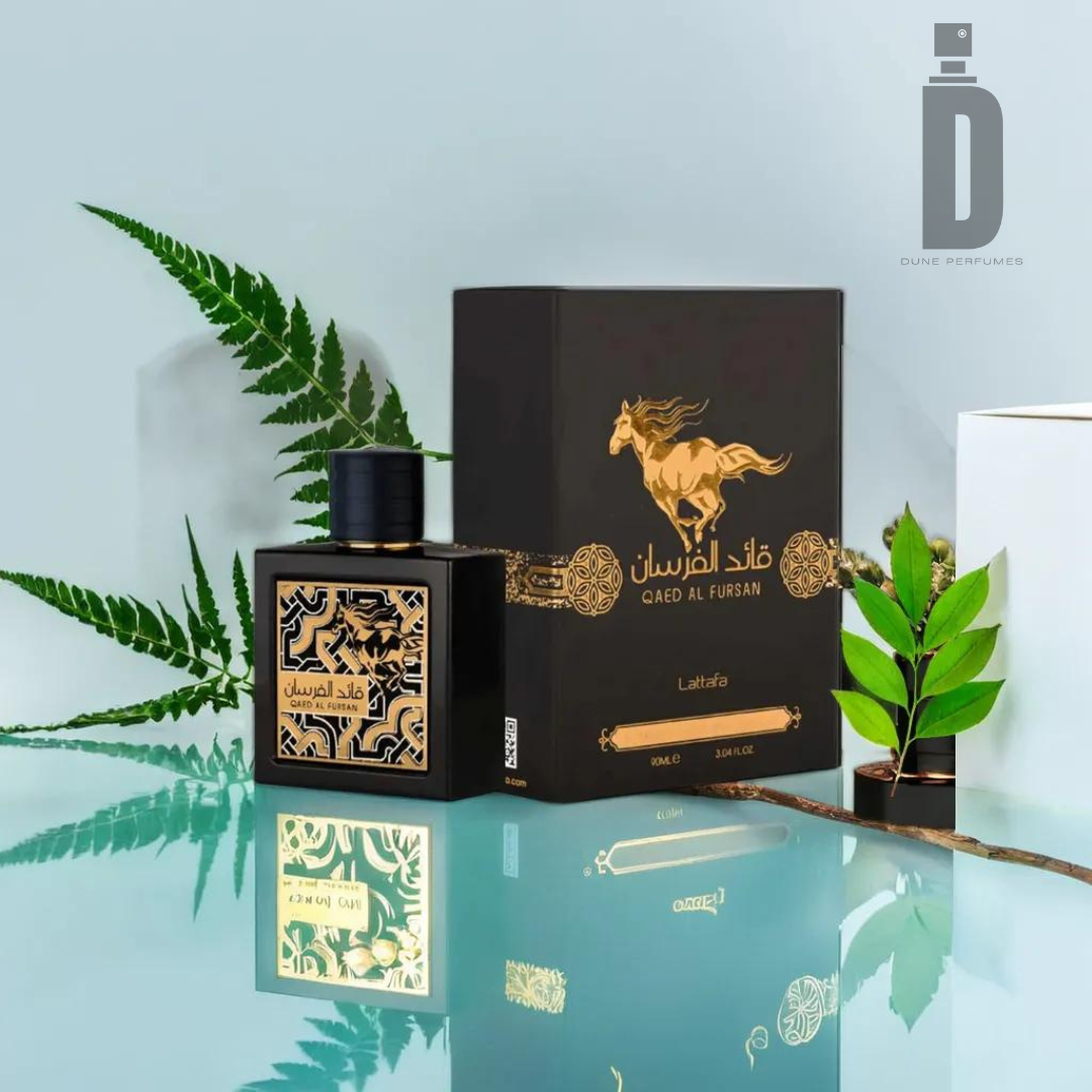 An elegant 90ml Eau de Parfum bottle with intricate designs sits beside its matching black and gold box labeled "Qaed Al Fursan 90ml EDP - Lattafa," exuding an exotic fragrance. The reflection of the bottle and box is visible on the glass surface, while green plants and the Dune Perfumes logo adorn the background.
