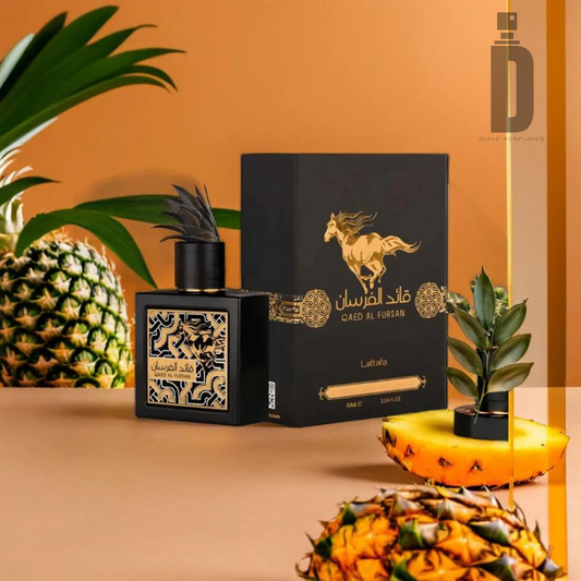 A stylish black perfume bottle with a decorative cap, holding the exotic fragrance of Qaed Al Fursan 90ml EDP by Lattafa, sits next to its elegant black and gold packaging featuring an illustration of a horse. Pineapples, including a sliced piece with leaves, are artistically arranged around the bottle against a warm beige background.