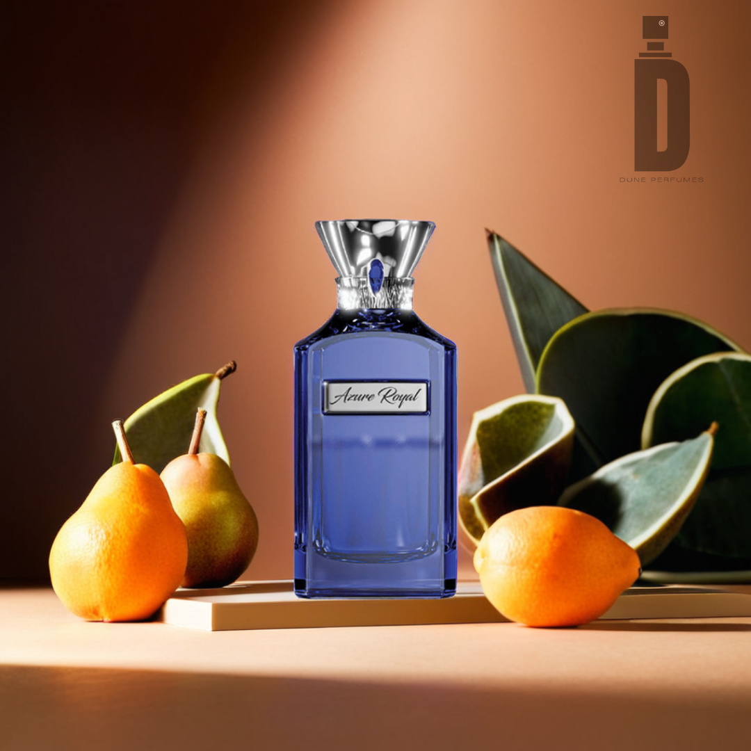 A blue perfume bottle labeled "Azure Royal 100ml EDP - Ahmed Al Maghribi" with a silver cap is placed on a reflective surface. Surrounding the bottle are fresh pairs of pears, some sliced open, and large green leaves. The captivating fragrance glows warmly in the background with the "Ahmed Al Maghribi" logo in the top right.