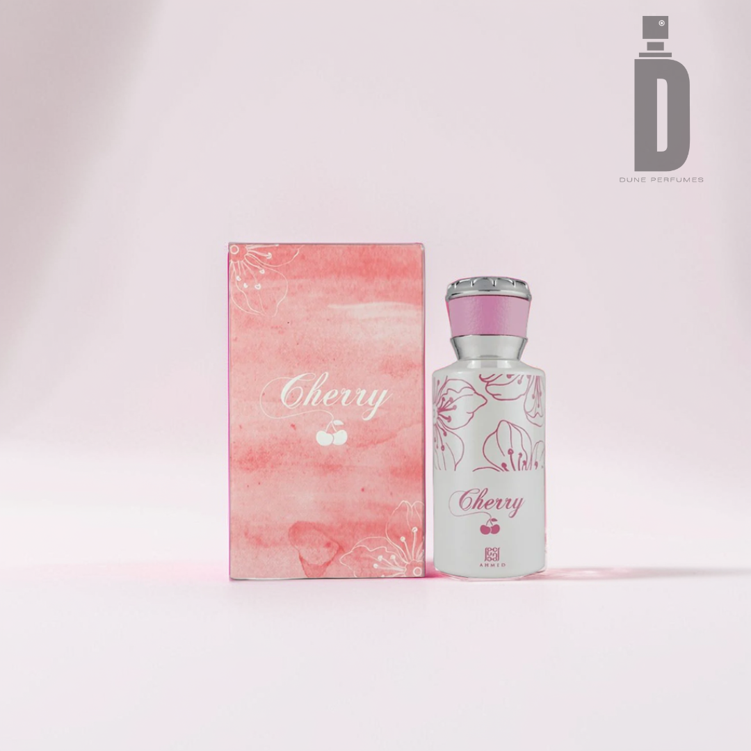 A elegantly designed perfume bottle labeled "Cherry 50ml EDP - Ahmed Al Maghribi," exuding a fruity sweetness, is placed beside its matching pink and white box. The box features delicate cherry blossom illustrations with a pink watercolor background. The Dune Perfumes logo in the top right corner adds a lasting impression, emphasizing its premium quality.
