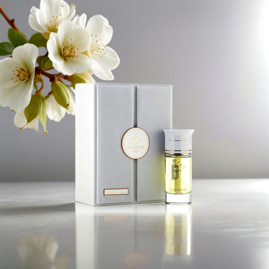 A white perfume box and a glass bottle labeled "Kashmir Musk 100ml EDP - Arabian Oud" by Arabian Oud rest on a reflective surface beside white flowers, highlighting the elegance of this luxury fragrance against a soft grey background.