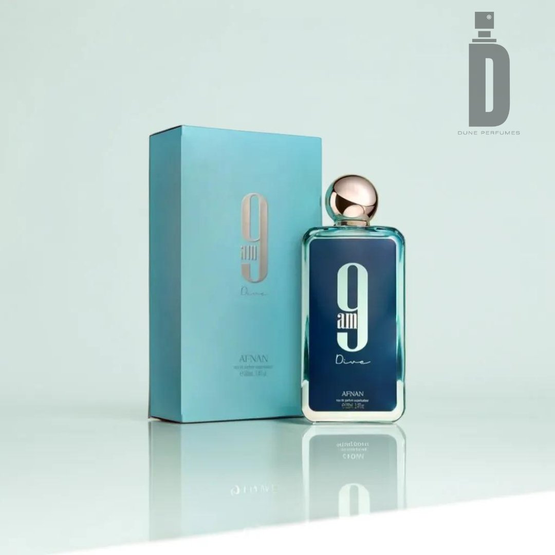 A rectangular bottle of 9am Dive 100ml EDP - Afnan, known for its refreshing fragrance, is displayed next to its matching blue box. The bottle features a metallic cap and "9 AM Dive" written on the front. The Afnan logo is visible in the top right corner of the image.