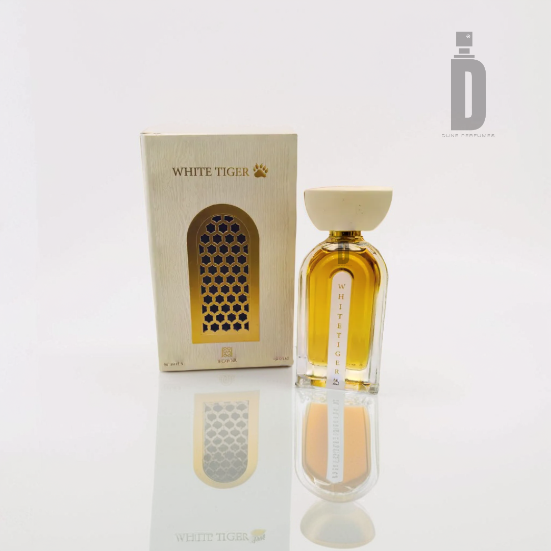 The "White Tiger 100ml EDP" by Ahmed Al Maghribi stands elegantly beside its cream-colored box, adorned with a golden paw design that exudes untamed beauty. The bottle, filled with amber liquid and capped in a matching cream hue, embodies the raw power of the White Tiger fragrance from Ahmed Al Maghribi.