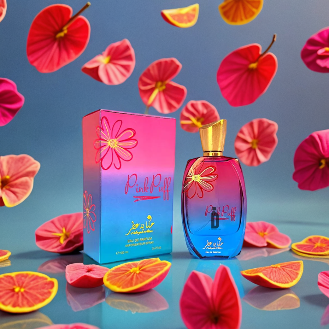 A PinkPuff 100ml EDP by Hekayat Attar and its box are set against a blue background with floating pink flowers and citrus slices, creating a vibrant, playful display.