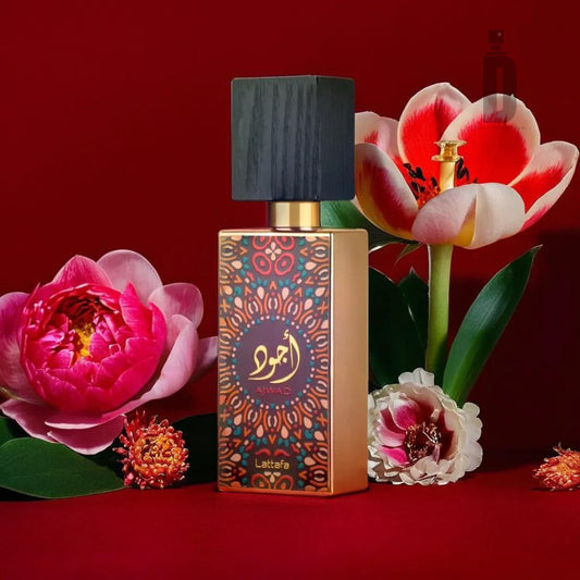 A perfume bottle featuring an intricate gold and red design, labeled "Ajwad 60ml EDP - Lattafa," is set against a rich red background. Surrounded by vibrant peonies and lilies, this sophisticated perfume from Lattafa has a black, square cap. Indulge in the luxurious scent of Ajwad fragrance.