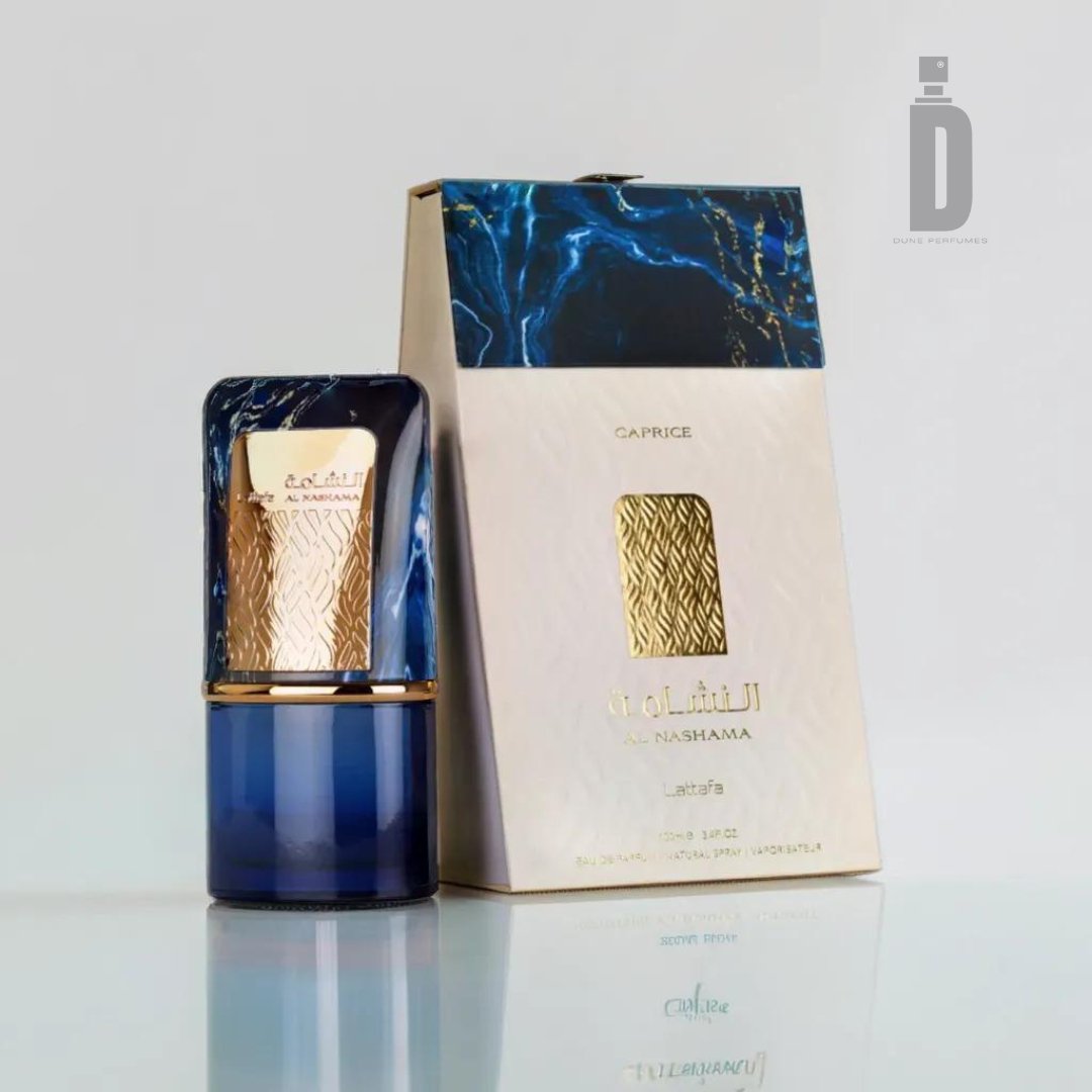 A small, elegant blue and gold perfume bottle stands in front of its box. The bottle has a modern gold cap adorned with intricate patterns, embodying the sophisticated fragrance within. The box, labeled "Al Nashama Caprice 100ml EDP - Lattafa" in both English and Arabic, features white and blue hues that hint at an herbal freshness.